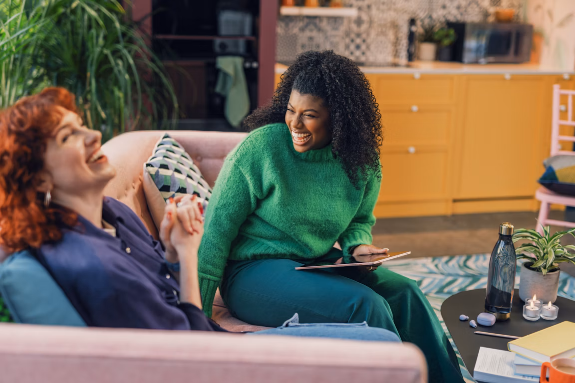 Two happy women laughing on a couch